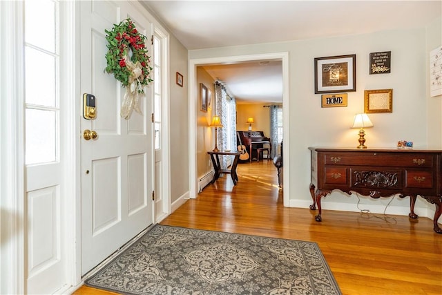 foyer entrance featuring baseboards, a baseboard heating unit, and light wood-style floors