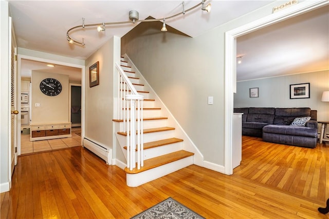 staircase with hardwood / wood-style floors, rail lighting, baseboards, and baseboard heating