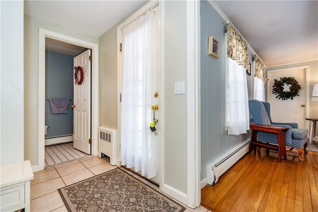 corridor with a baseboard heating unit, radiator, light tile patterned flooring, and baseboard heating