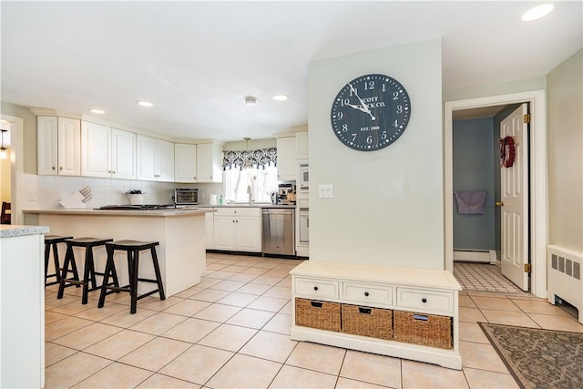 kitchen with radiator, light tile patterned floors, a breakfast bar, dishwasher, and backsplash