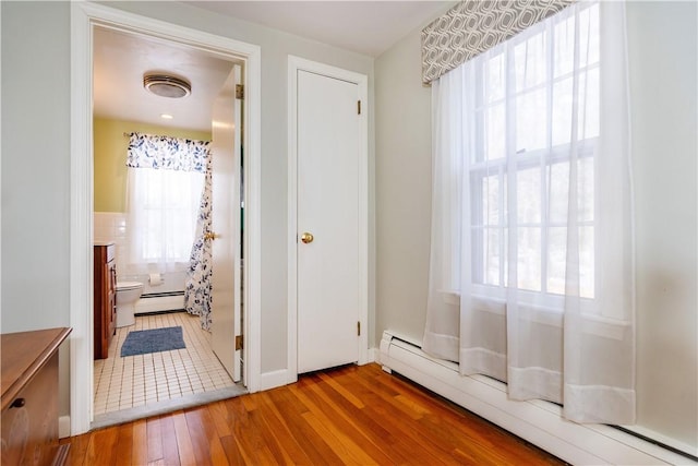 interior space featuring a baseboard heating unit, hardwood / wood-style flooring, and a wealth of natural light