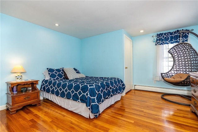 bedroom with recessed lighting, a baseboard radiator, and wood finished floors