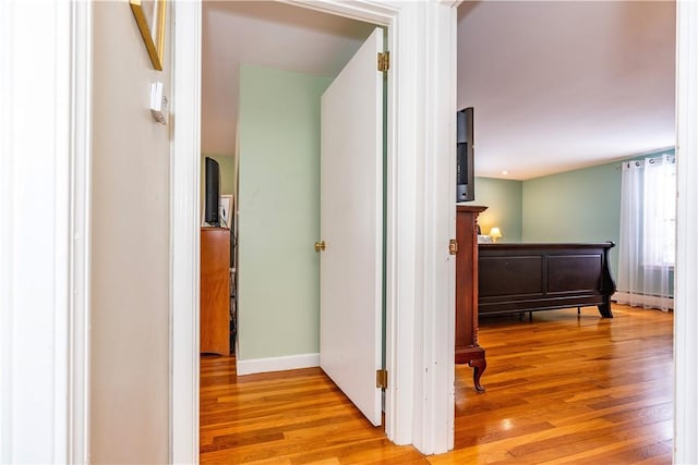 hall featuring a baseboard heating unit, baseboards, and light wood-style floors