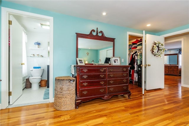 bedroom with wood finished floors, recessed lighting, a spacious closet, a closet, and ensuite bathroom