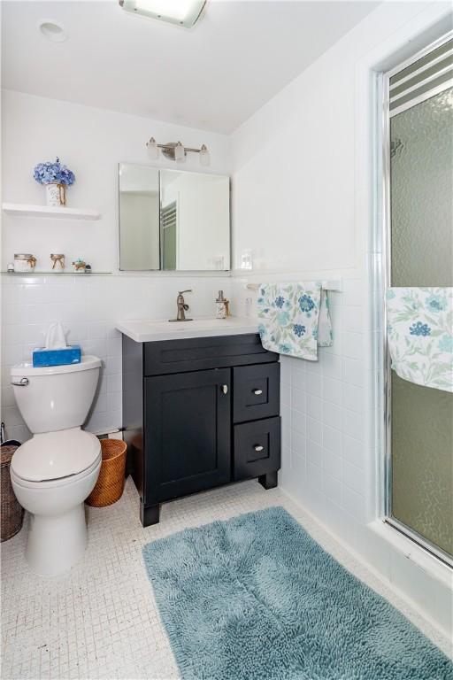 full bathroom with vanity, tile walls, a stall shower, and tile patterned floors