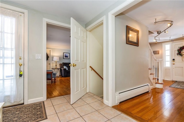 entryway with light tile patterned floors, a baseboard heating unit, and track lighting