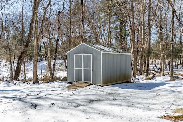 snow covered structure featuring a storage unit and an outdoor structure