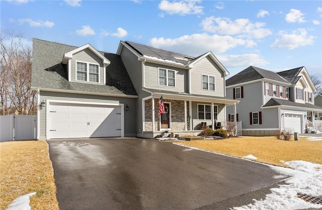 traditional home with solar panels, fence, covered porch, driveway, and a gate