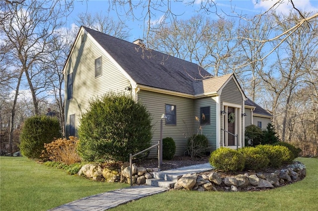 view of side of home with a yard and roof with shingles