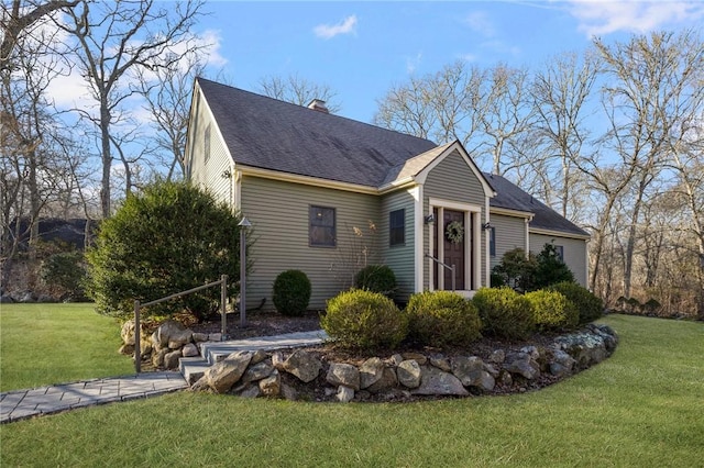 view of front facade featuring a chimney, a front yard, and a shingled roof