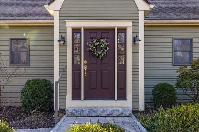 view of exterior entry with a shingled roof