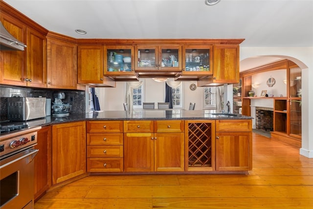 kitchen with range, a sink, brown cabinetry, wall chimney range hood, and recessed lighting