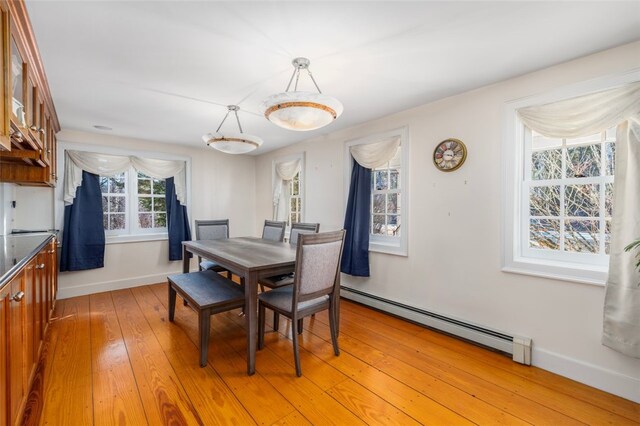 dining room featuring baseboard heating, light wood-style floors, and baseboards