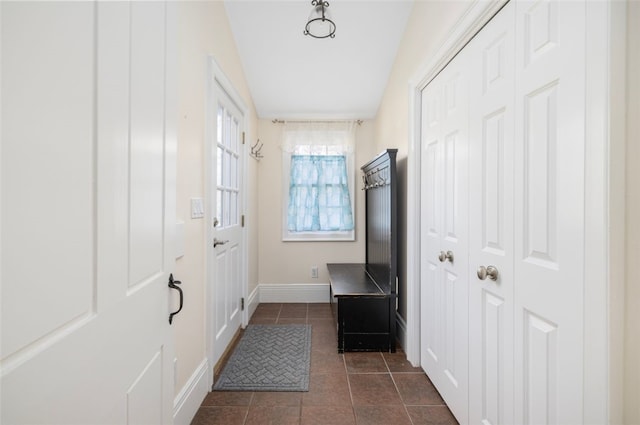 mudroom with dark tile patterned flooring and baseboards