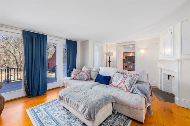 bedroom featuring access to outside, light wood-type flooring, a fireplace with flush hearth, and baseboards