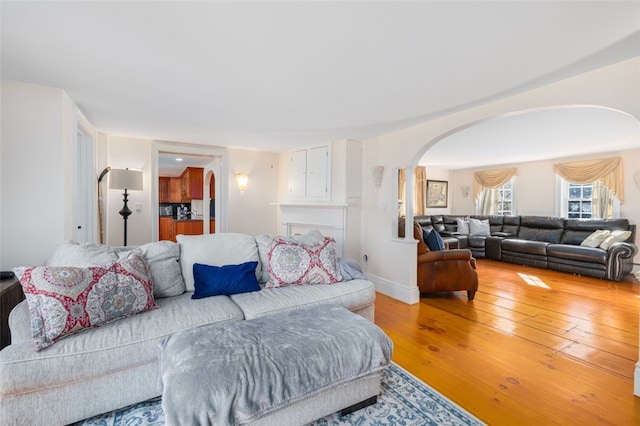 living area with arched walkways and hardwood / wood-style flooring