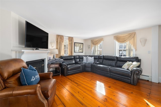 living area featuring a fireplace, a baseboard heating unit, and wood-type flooring