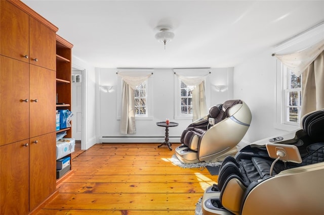 living area with a baseboard heating unit, light wood-type flooring, and baseboards