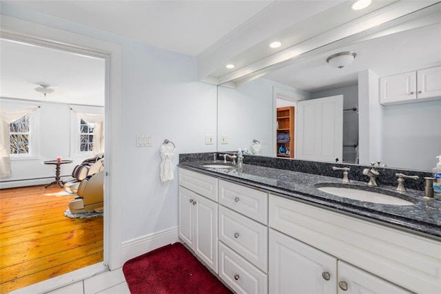 full bathroom with recessed lighting, double vanity, baseboards, and a baseboard heating unit