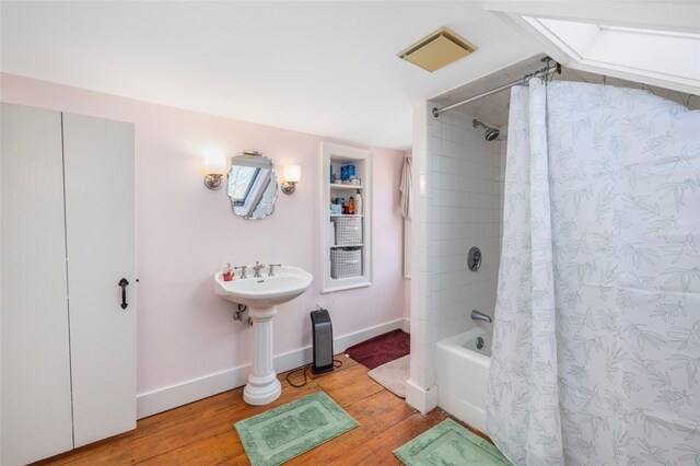 full bathroom with wood finished floors, shower / bathtub combination with curtain, and baseboards