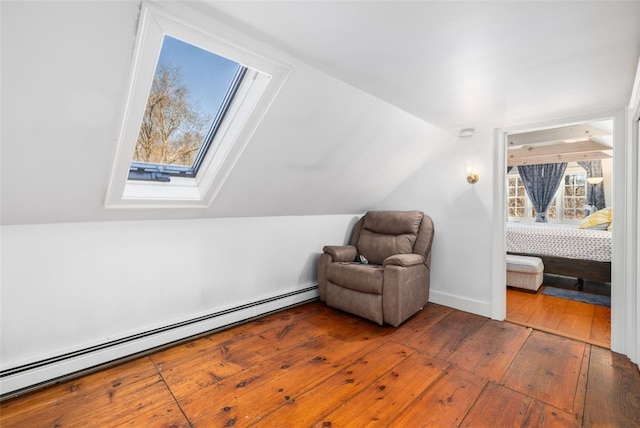 sitting room with a baseboard radiator, hardwood / wood-style flooring, vaulted ceiling, and a skylight