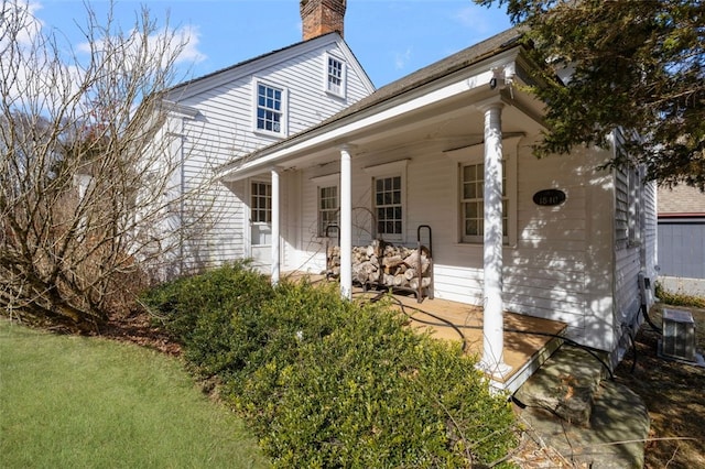 view of front of property with cooling unit, a chimney, and a front yard