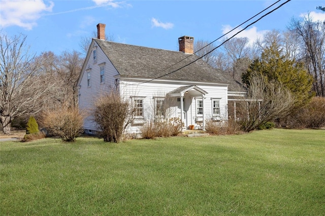 back of house featuring a lawn, a chimney, and roof with shingles