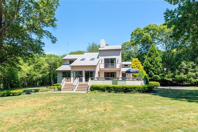 view of front facade with a wooden deck, a chimney, and a front yard