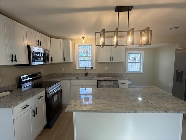 kitchen featuring light stone counters, a sink, stainless steel appliances, white cabinets, and a center island