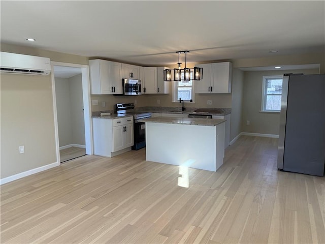 kitchen with light wood finished floors, a healthy amount of sunlight, a wall mounted air conditioner, and stainless steel appliances