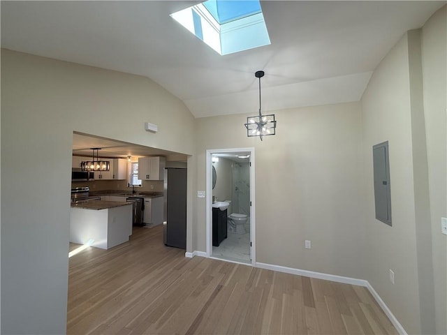 interior space with baseboards, lofted ceiling with skylight, electric panel, light wood-style flooring, and a notable chandelier