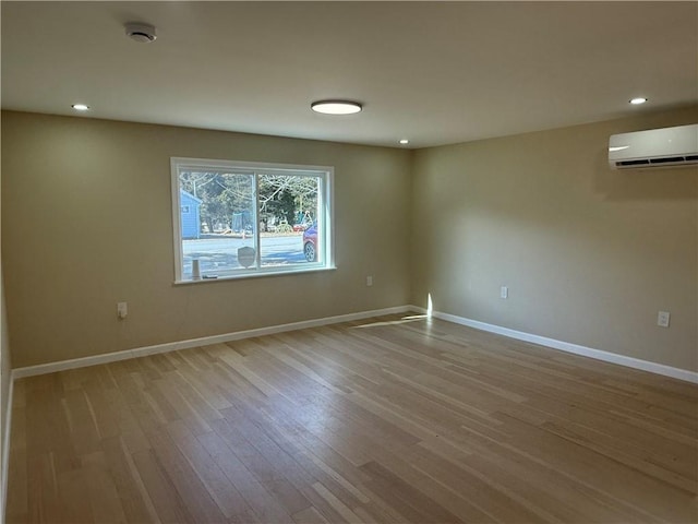 spare room with recessed lighting, baseboards, a wall unit AC, and wood finished floors