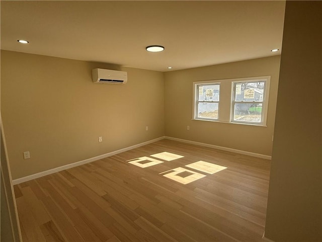 spare room featuring recessed lighting, a wall mounted air conditioner, baseboards, and wood finished floors