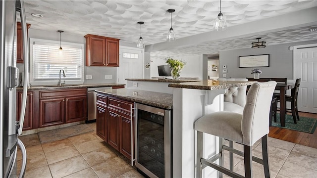 kitchen featuring a sink, a center island, stainless steel appliances, wine cooler, and a breakfast bar area