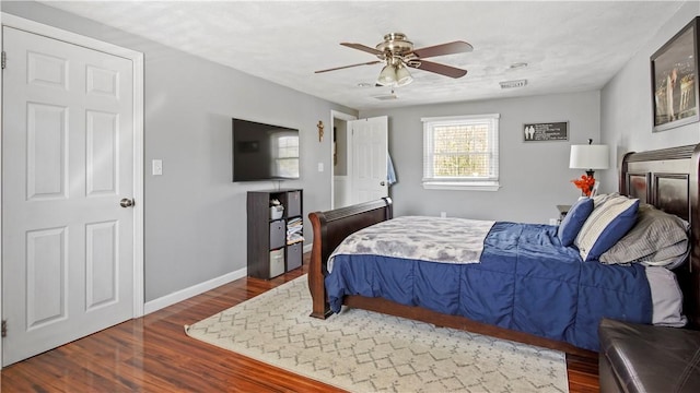 bedroom featuring ceiling fan, baseboards, and wood finished floors