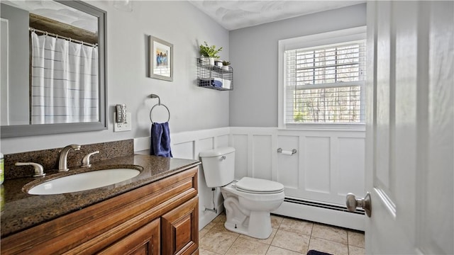 full bathroom featuring tile patterned flooring, a wainscoted wall, toilet, baseboard heating, and vanity