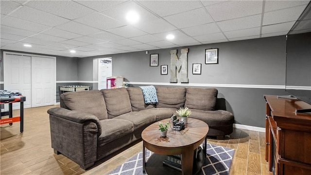 living area with recessed lighting, baseboards, a paneled ceiling, and light wood-style floors