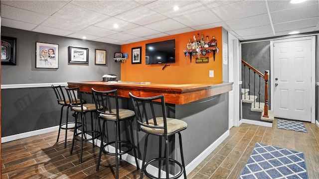 bar with stairway, baseboards, a dry bar, and wood tiled floor