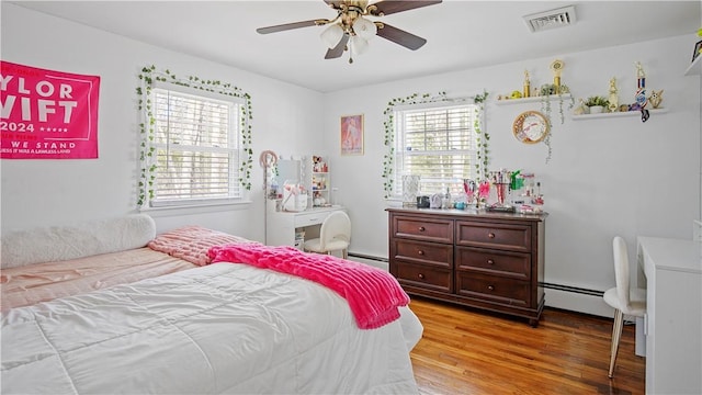 bedroom with visible vents, a baseboard radiator, light wood-style flooring, ceiling fan, and baseboard heating