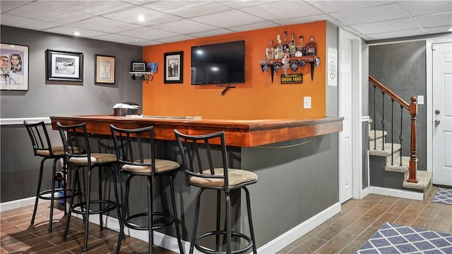 bar featuring stairway, bar area, and wood tiled floor