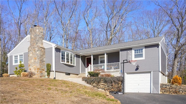 ranch-style house featuring a front yard, covered porch, a chimney, a garage, and driveway