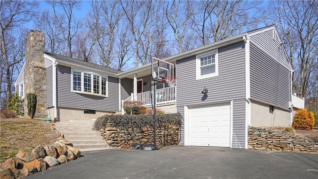 single story home with aphalt driveway, a chimney, and an attached garage