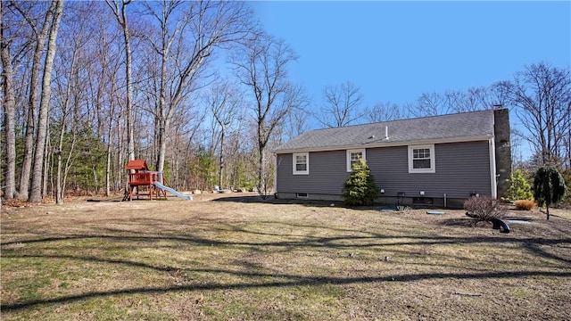 back of property featuring a chimney, a playground, and a yard