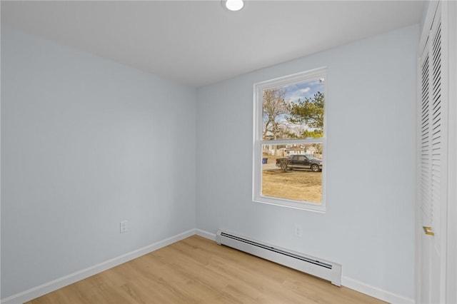 spare room with baseboards, baseboard heating, and light wood finished floors