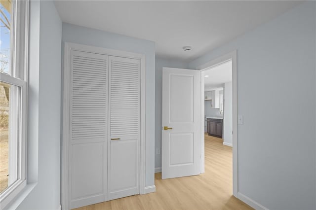 hallway featuring light wood-style flooring and baseboards