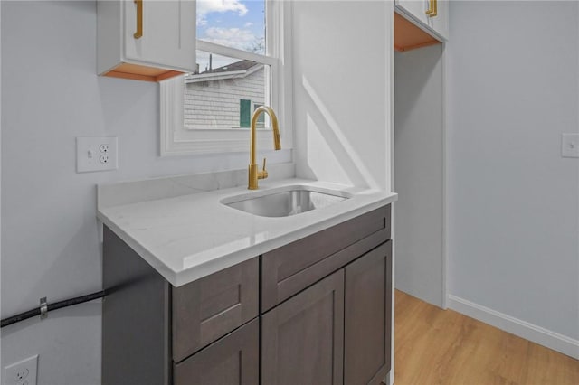 kitchen with a sink, baseboards, and light wood-style floors