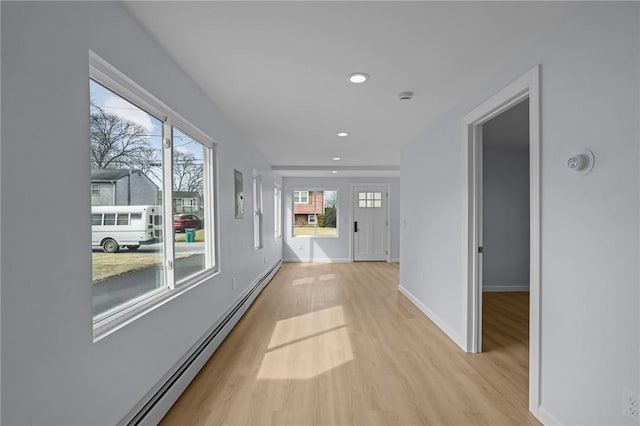 corridor with recessed lighting, a baseboard radiator, baseboards, and light wood-style flooring