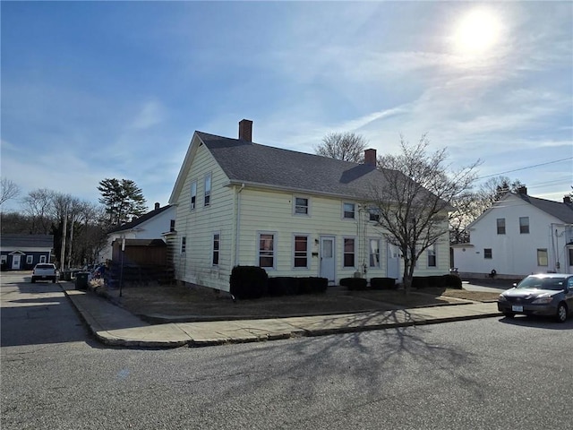 view of front facade featuring a shingled roof and a chimney