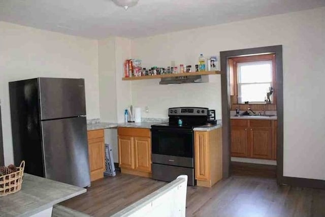 kitchen featuring light wood-style flooring, electric stove, freestanding refrigerator, and a sink