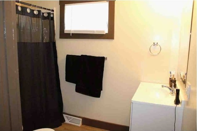 bathroom with a shower with shower curtain, visible vents, baseboards, and vanity